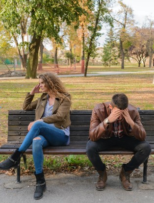 Photo of an upset man and woman sitting apart from each other outside on a bench. Is your depression affecting your relationship? Learn how depression counseling can help you manage your depression symptoms and live a happier life.