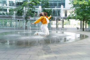 Woman jumping in a fountain. If you are experiencing body image issues, don't go through it alone. We offer in-person and online therapy in Georgia for body positive therapy. Call now and begin body image therapy in Georgia soon!