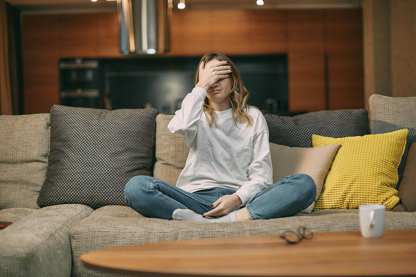 Photo of a young woman sitting on a couch with her hand on her forehead looking upset. Are you feeling lonely and hopeless? Learn how depression treatment in Georgia can help you manage your symtpoms.
