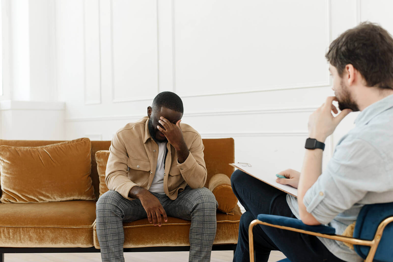 Photo of a black man looking upset and covering his face while speaking with his therapist. Struggling to control your emotions? Are they causing you to act out? With dbt therapy in Georgia you can meet with a skilled therapist to learn the skills to control your unwanted behaviors.