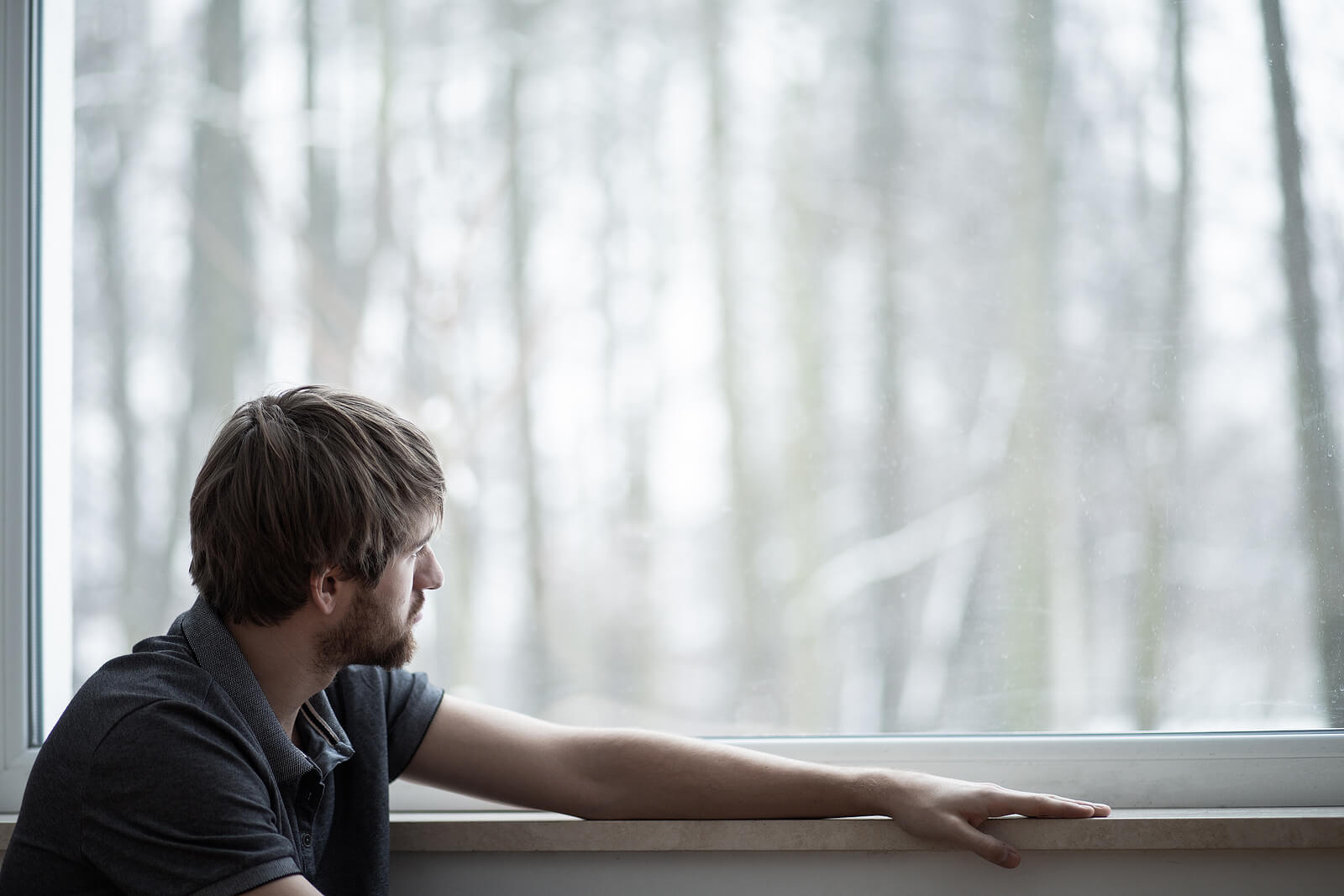 Photo of a man looking upset out a window. Looking to recover from sexual addiction? Get support with sexual addiction therapy in Georgia to start your recovery.