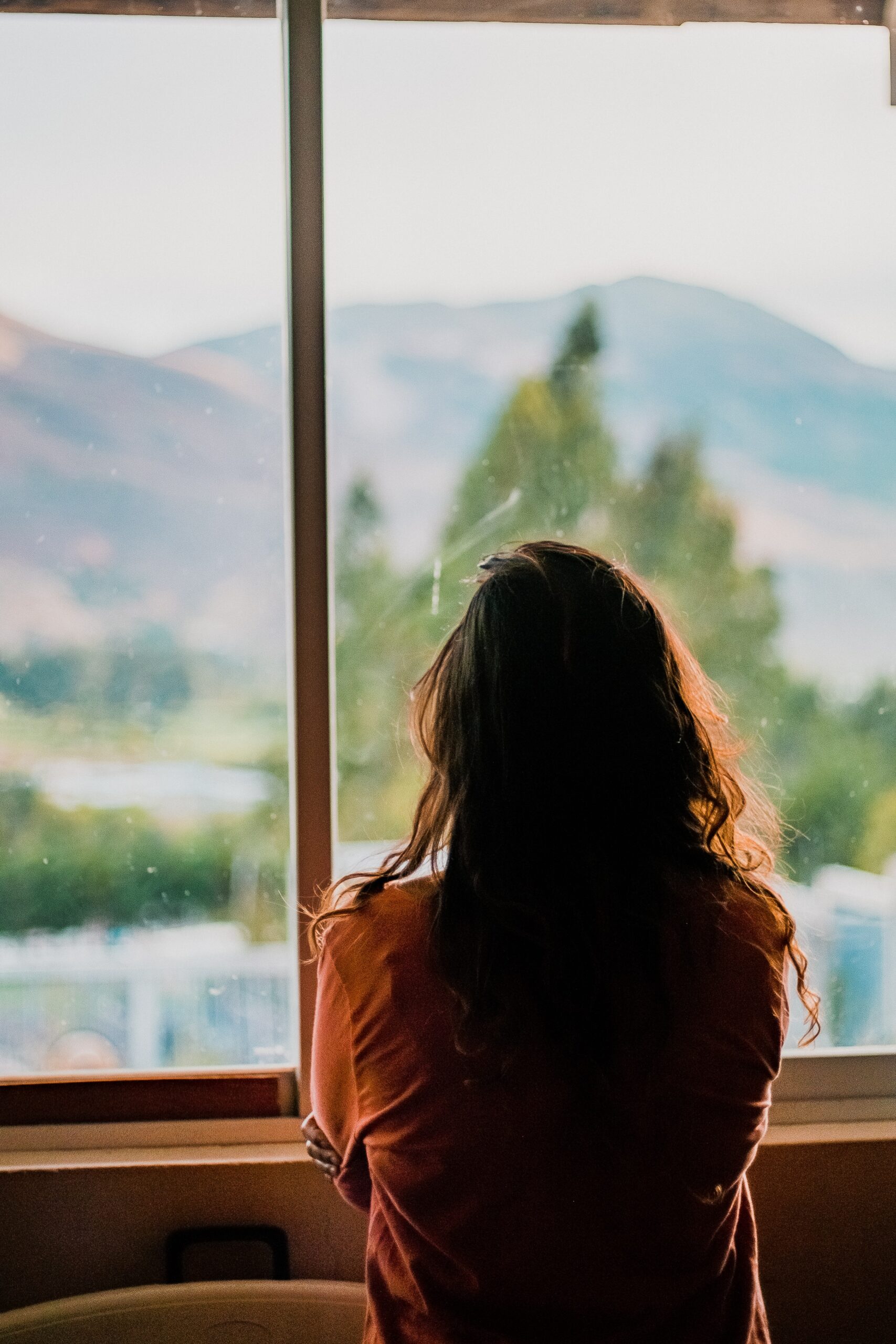 Woman looking out of window looking sad