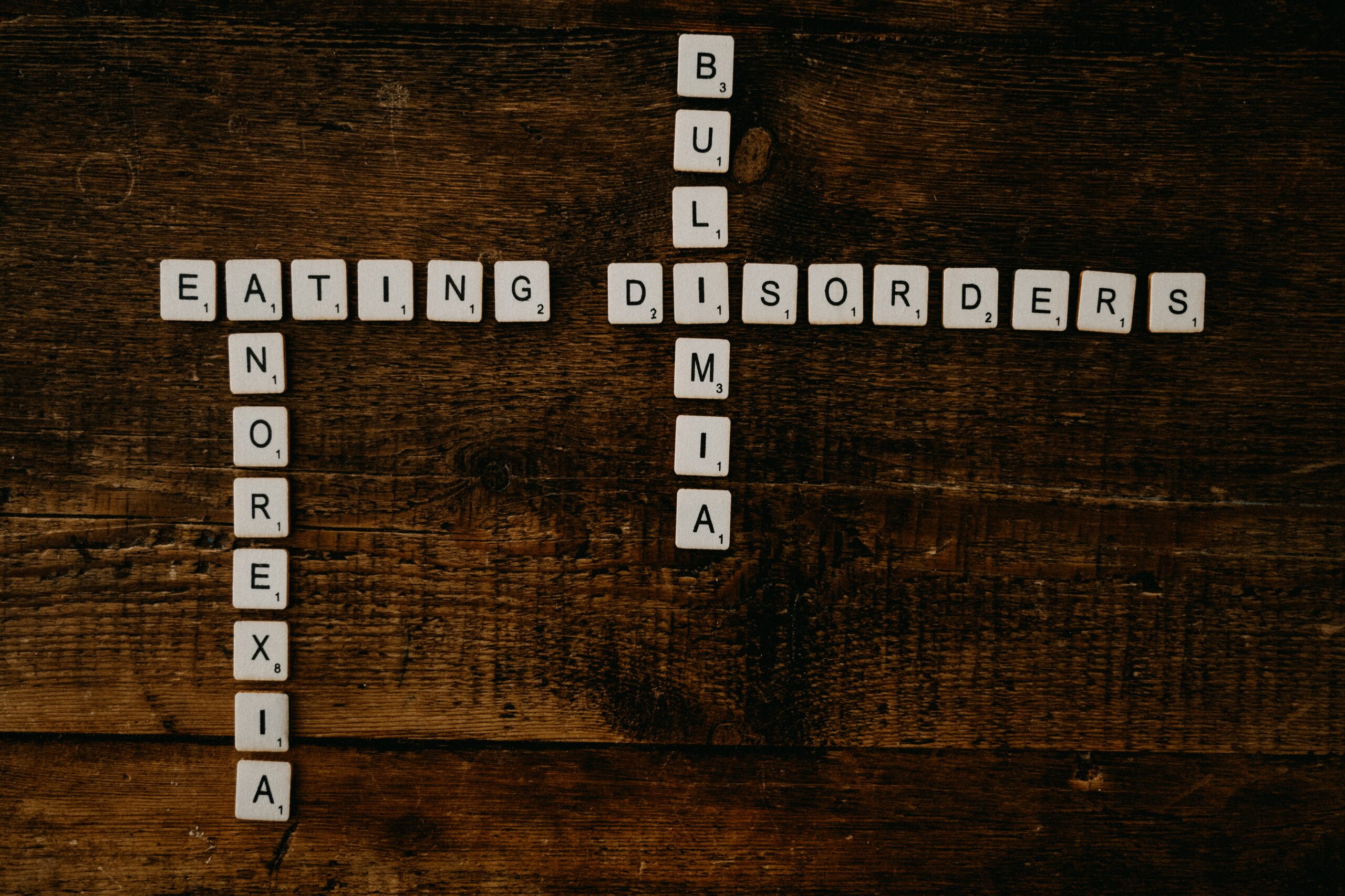 Scrabble Letters spelling the word Eating Disorders horizonatlly. The a in Eating spells anorexia vertiacally and the i in disorders is a part of the word bulimia spelled vertically
